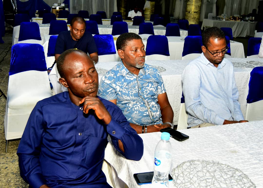 Three attendees seated at a table, one resting his chin on his hand