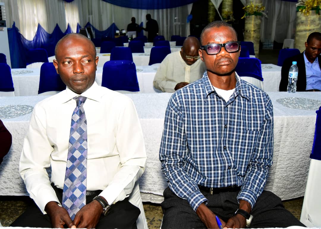 Two attendees seated side by side, one holding a pen