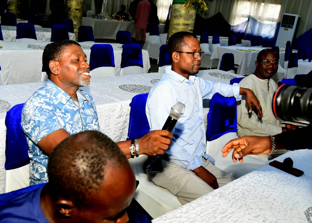 Seated attendees smiling as a microphone is passed between them