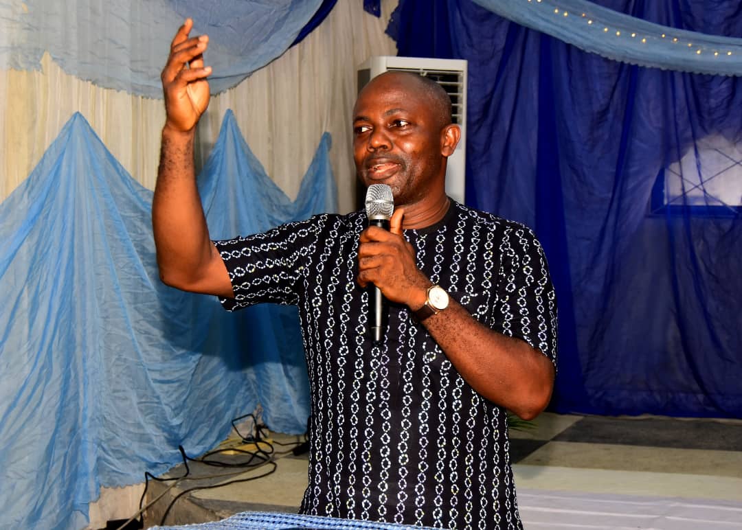 A man speaking into a microphone with his hand raised