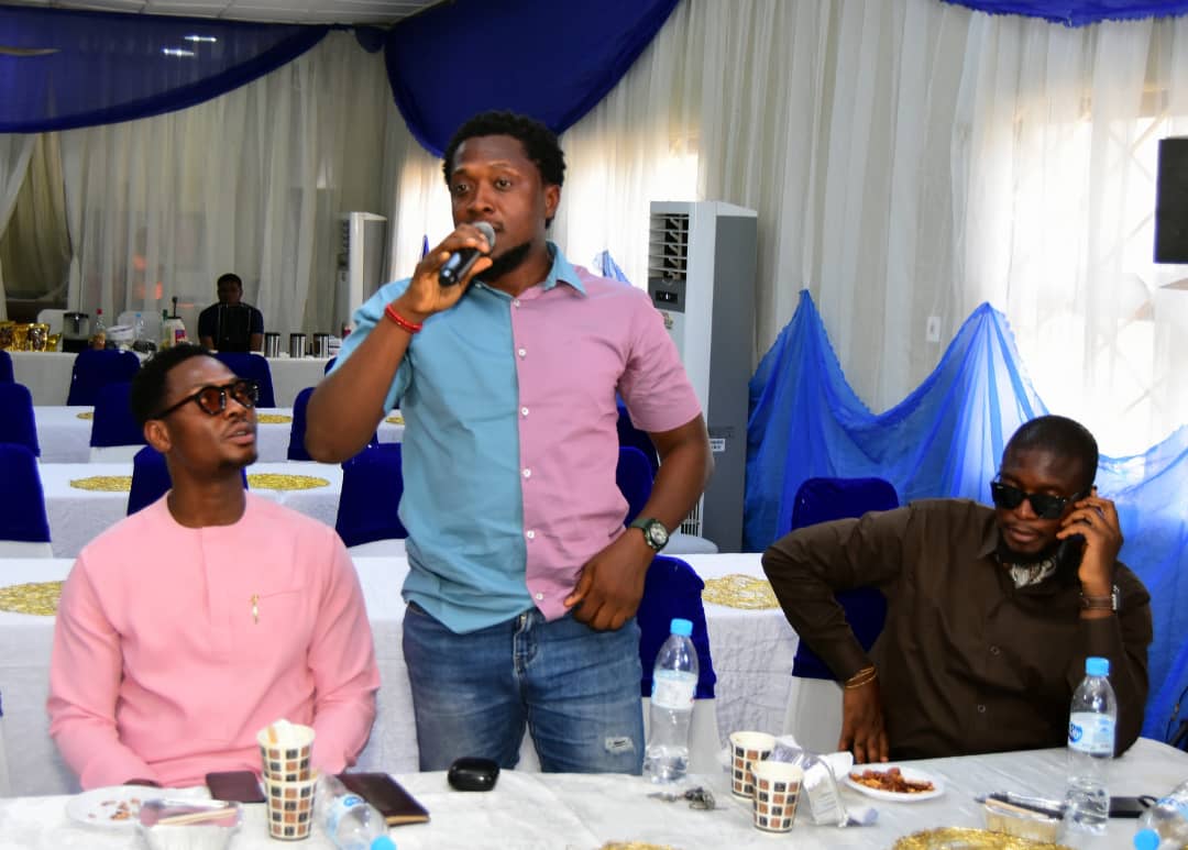 An attendee standing to speak into a microphone between two seated men